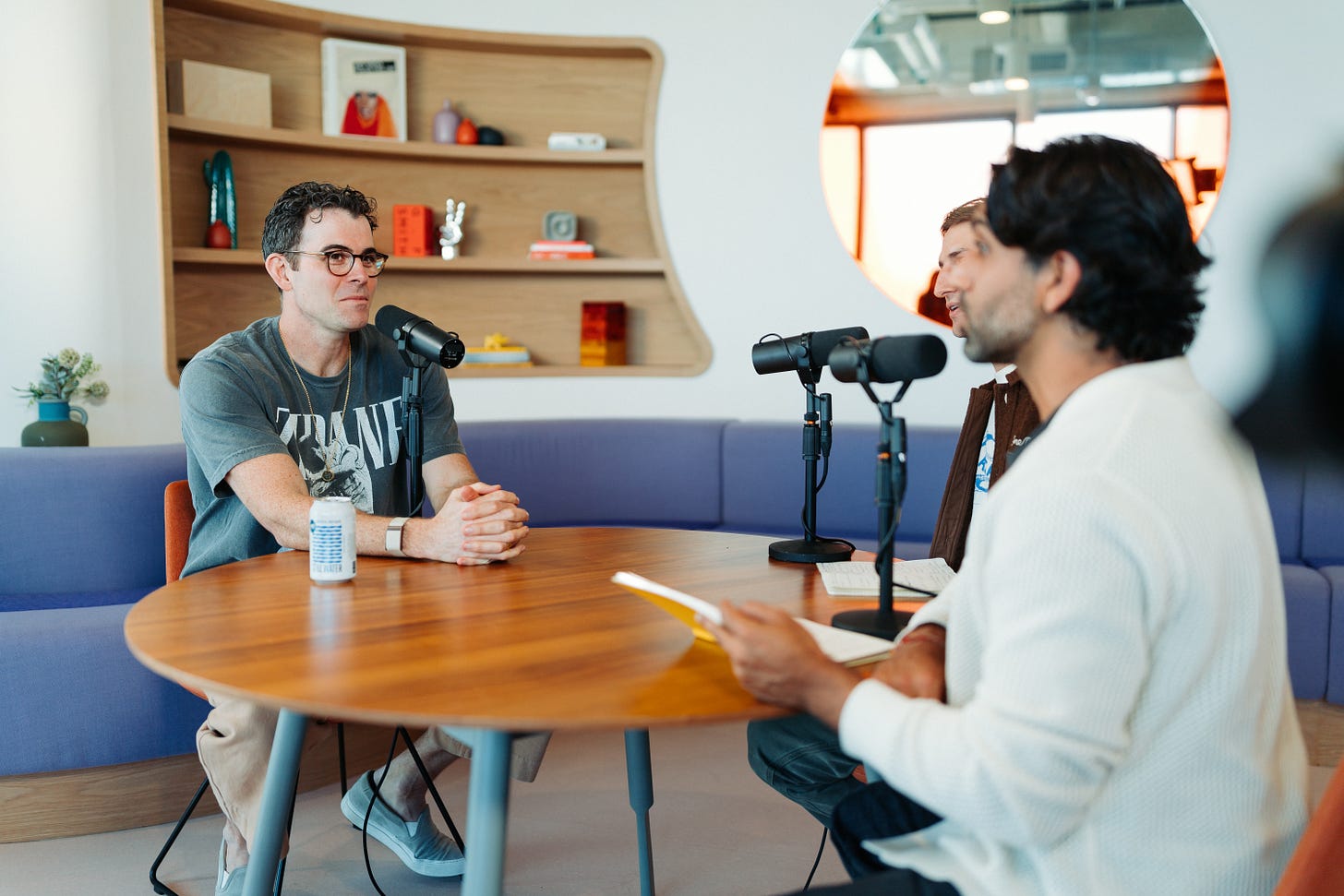 Instagram head Adam Mosseri sitting at a table with YouTubers Colin and Samir, there is a mic on the table in front of him