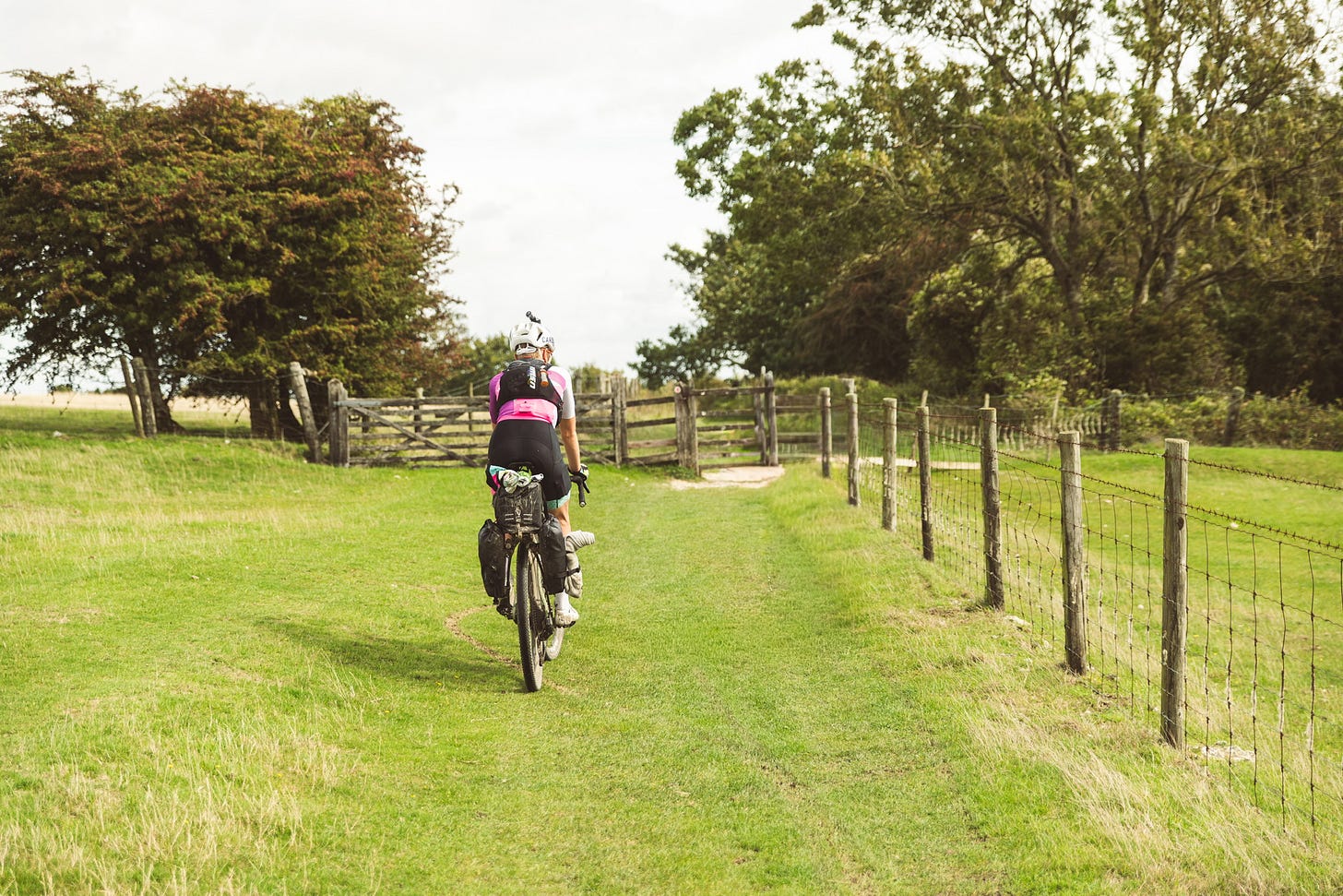 bicycle rider in field in the UK riding away from the camera