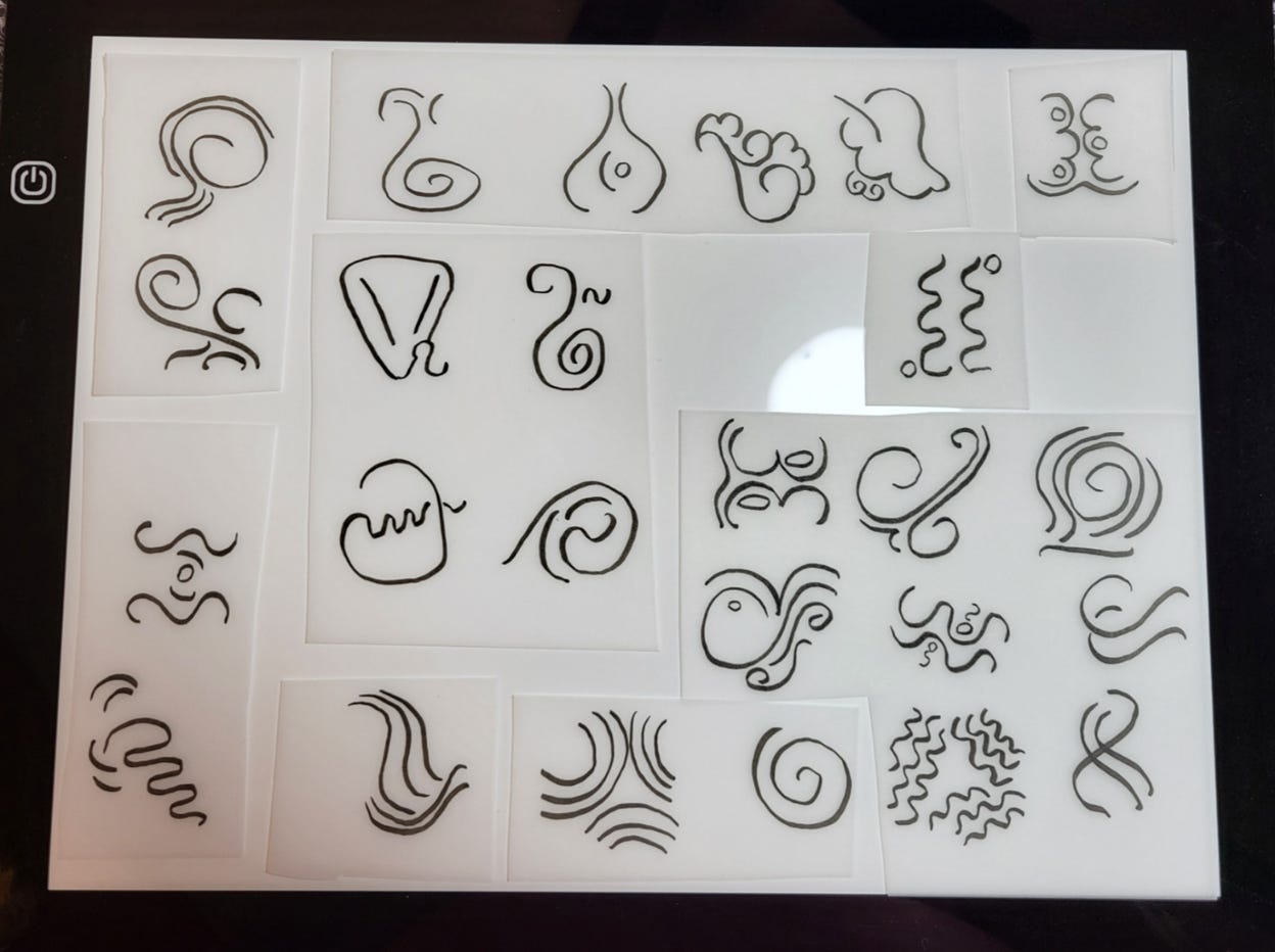 Hand-drawn glyphs on tracing paper and sitting a light source, preparation for scanning into digital files.