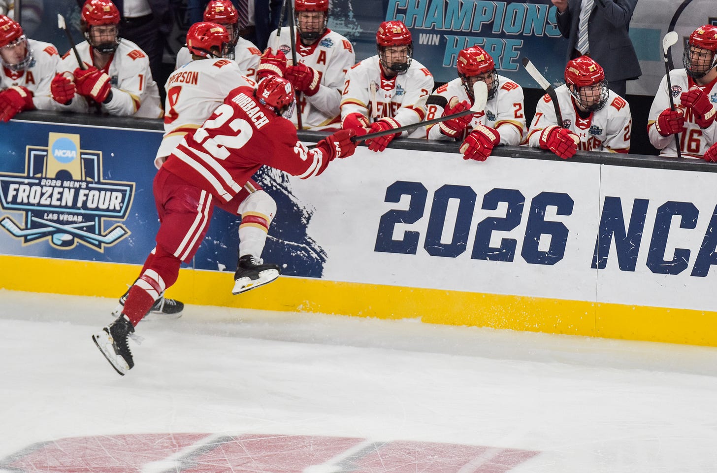 Jack Horbach makes strong check on Kristian Epperson in front of Denver Pioneer bench.
