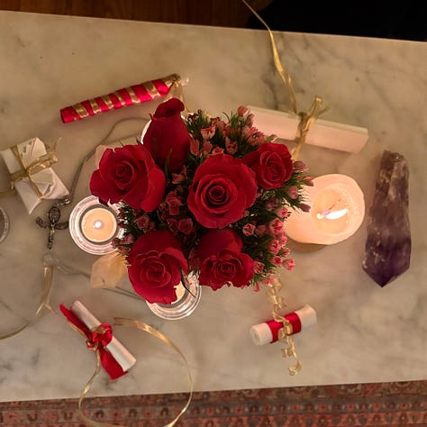 Hot pink roses, scrolls with red and gold ribbon, and crystals for travel ritual