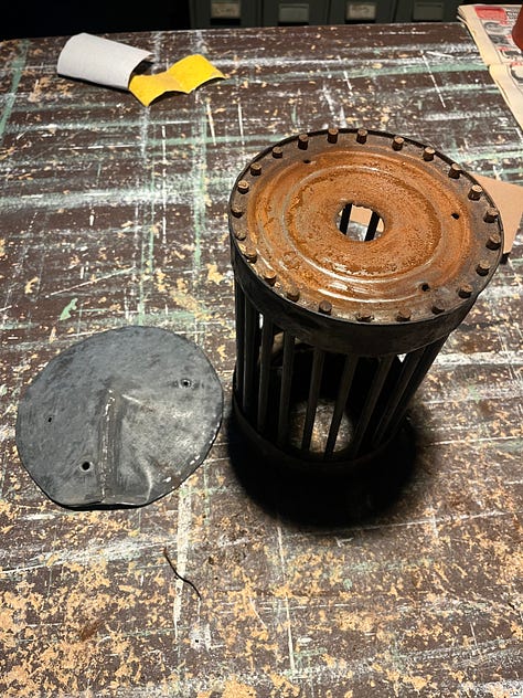 A wooden frame for storing and painitng wooden panels and tools and a series of coffee can lanterns in the process of being restored.