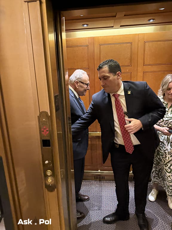 Man in a suit on an elevator reaches over to hit correct floor button Photo Matt also © www.askapol.com