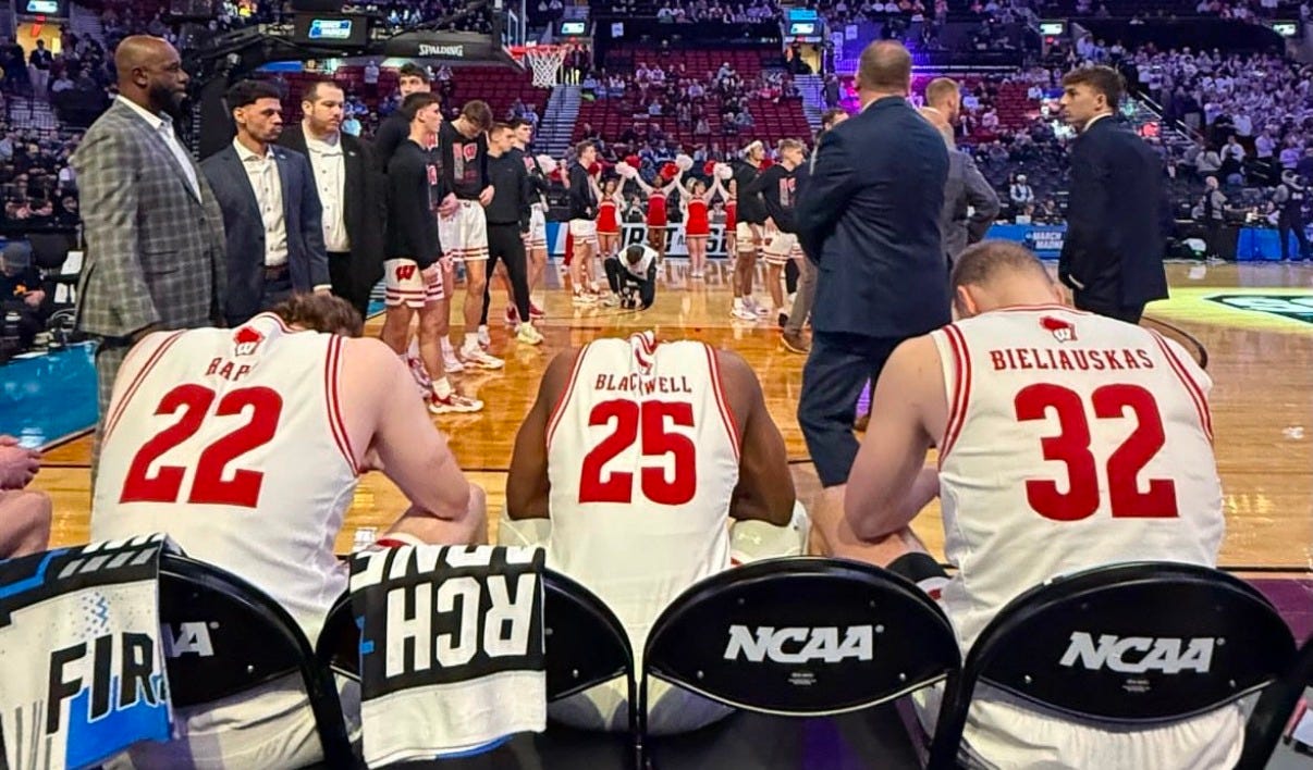 Wisconsin Badgers players Austin Rapp, John Blackwell, and Aleksas Bieliauskas sit on the bench during the starting lineups before an NCAA Tournament game.Wisconsin Badgers players Austin Rapp, John Blackwell, and Aleksas Bieliauskas sit on the bench during the starting lineups before an NCAA Tournament game. Photo credit: UW Athletics.