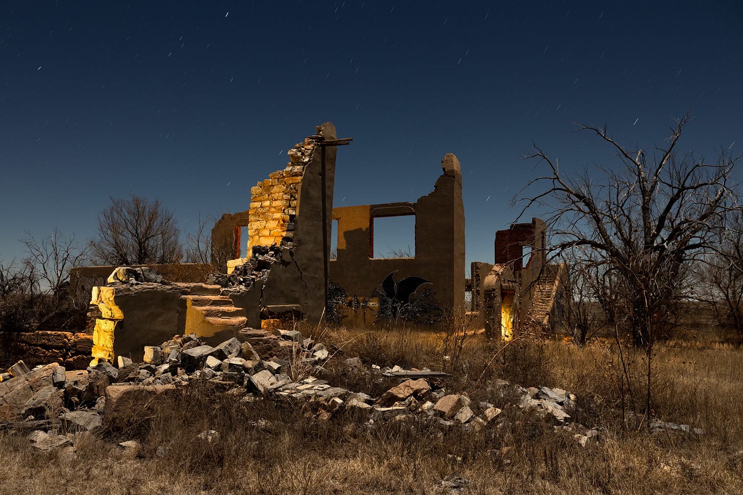 Crumbling stone brick building with yellow light glowing on the inside, under a starry night sky Crumbling stone brick building with yellow light glowing on the inside, under a starry night sky