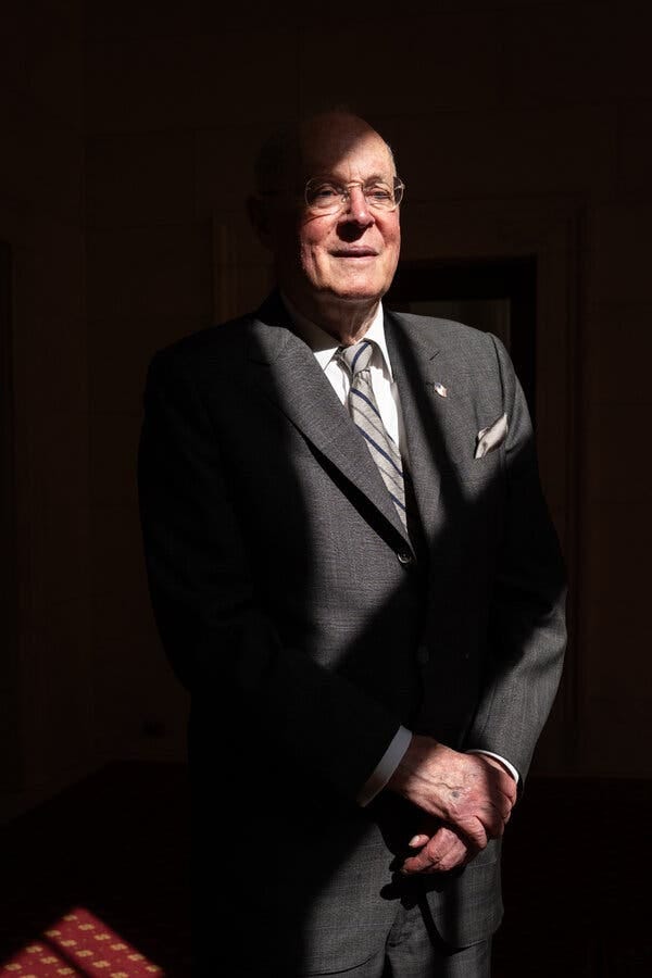A photo portrait of Justice Anthony M. Kennedy, wearing a gray suit and standing partially in shadows. A photo portrait of Justice Anthony M. Kennedy, wearing a gray suit and standing partially in shadows.
