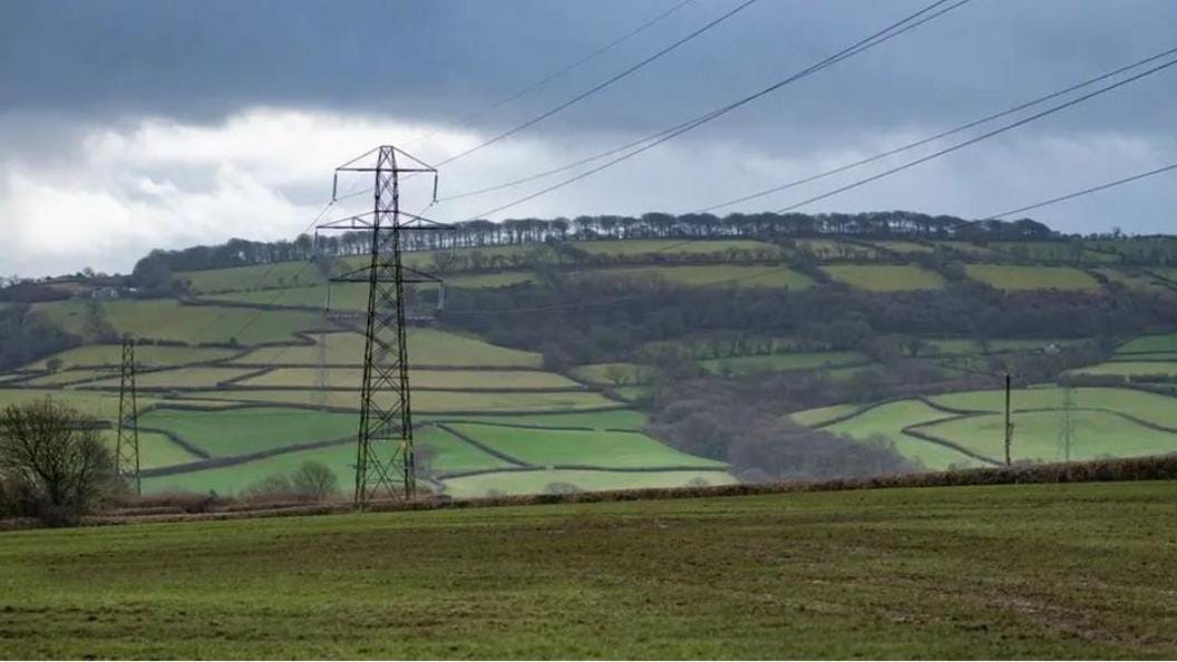 Pylons in field with fields and trees behind