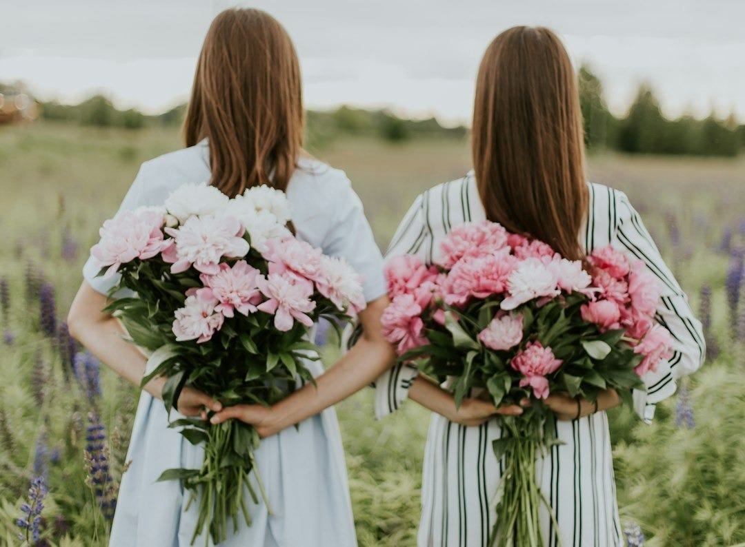 photo of two woman holding flower bouquets