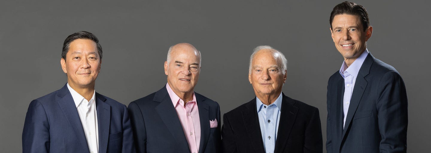 From left to right, Joe Bae, Henry Kravis, George Roberts, and Scott Nuttall stand in a line smiling at the camera. From left to right, Joe Bae, Henry Kravis, George Roberts, and Scott Nuttall stand in a line smiling at the camera.