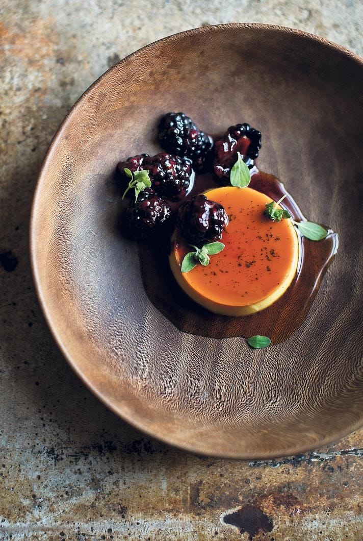This may contain: a small bowl filled with fruit and garnish on top of a wooden table