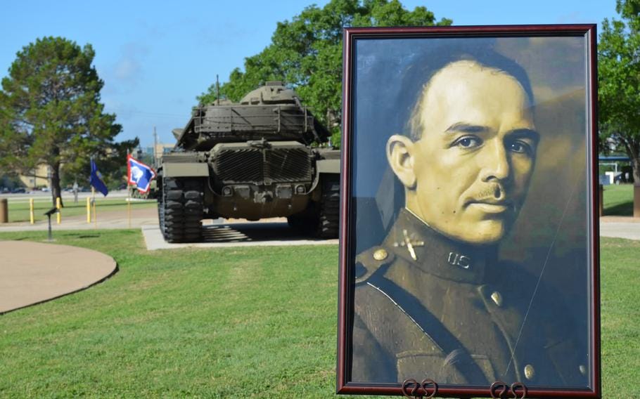 A portrait of Col. Robert B. Hood displayed on a lawn in front of the back of a tank. A portrait of Col. Robert B. Hood displayed on a lawn in front of the back of a tank.