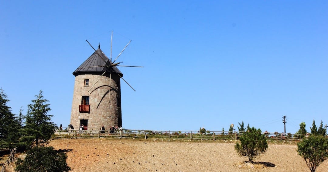 A windmill sitting on top of a dirt hill A windmill sitting on top of a dirt hill