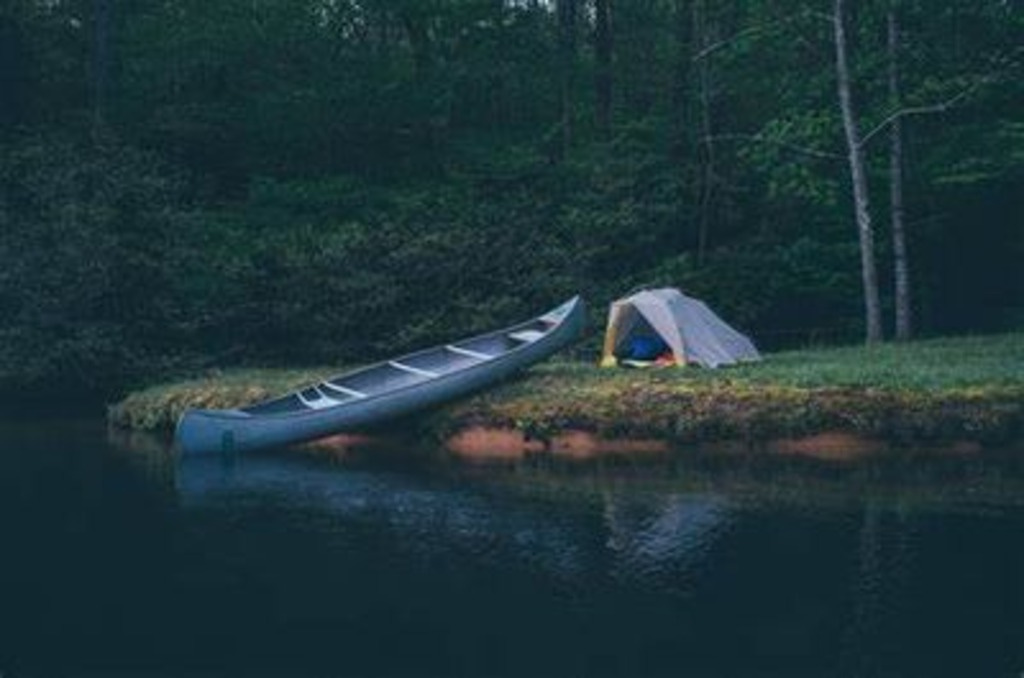 back country camping implies you do not drive there. A canoe is resting on the shoreleine beside a tent