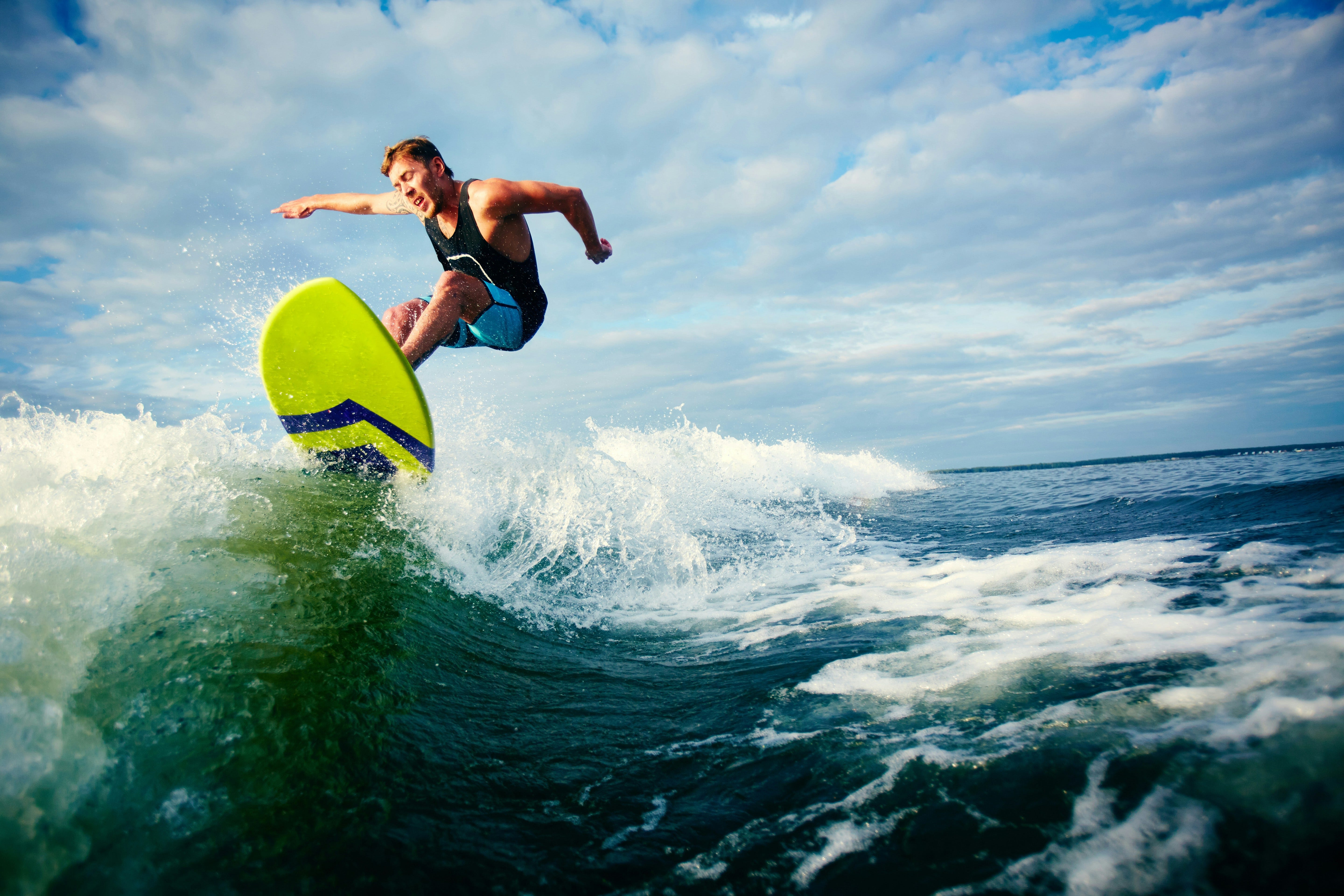 Surfer riding bright lime green surfboard above the way- Getty images