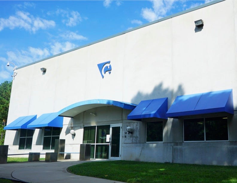The exterior of a Virginia Correctional Enterprises building is white with blue trim. 
