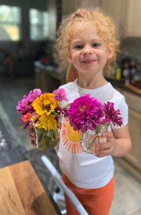 A child holding flowers in a kitchen

Description automatically generated