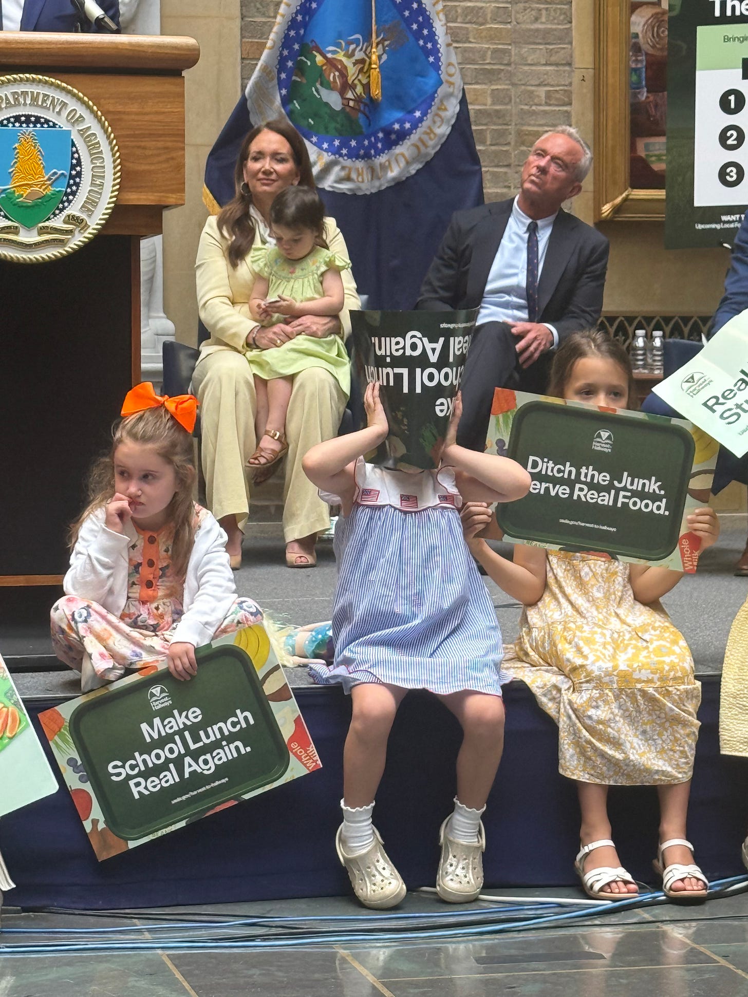 Children hold Make School Lunch Real Again and Ditch the Junk Serve Real Food signs at the USDA event