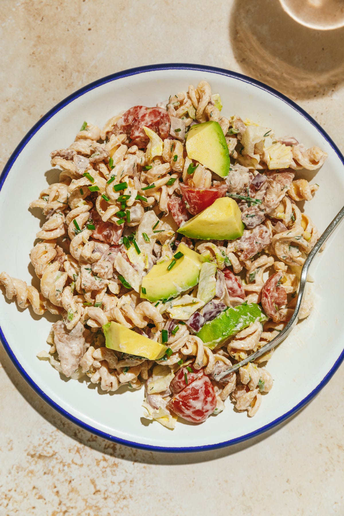 BLTA pasta salad on a blue rimmed plate.