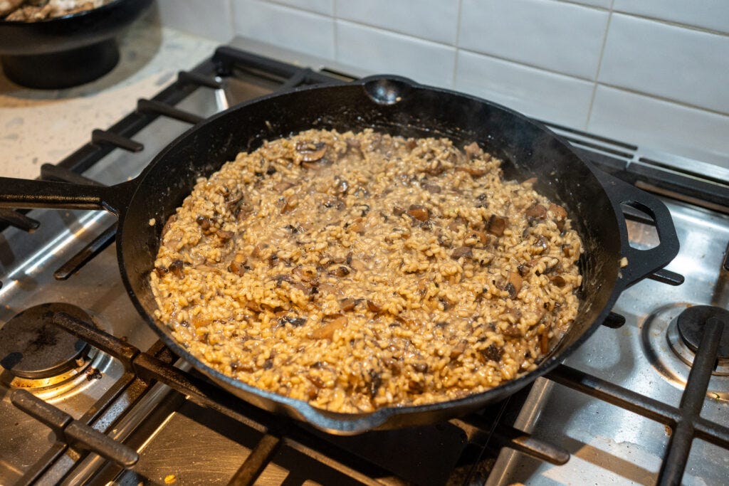 Warm stock bubbling and absorbing into a creamy, thick cast iron mushroom rice.