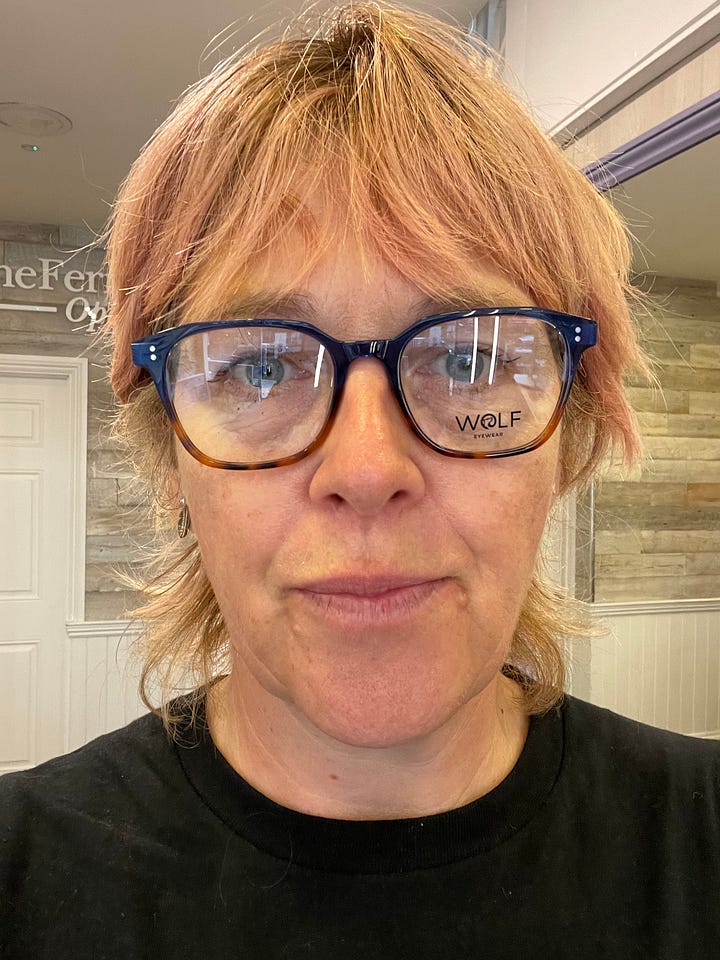 On the left, a glum middle aged woman in black glasses with sagging face. On the right the same woman in a hat and teal glasses, smizing to reveal the vaguely shiny cheekbones given to her by using Miracle Balm