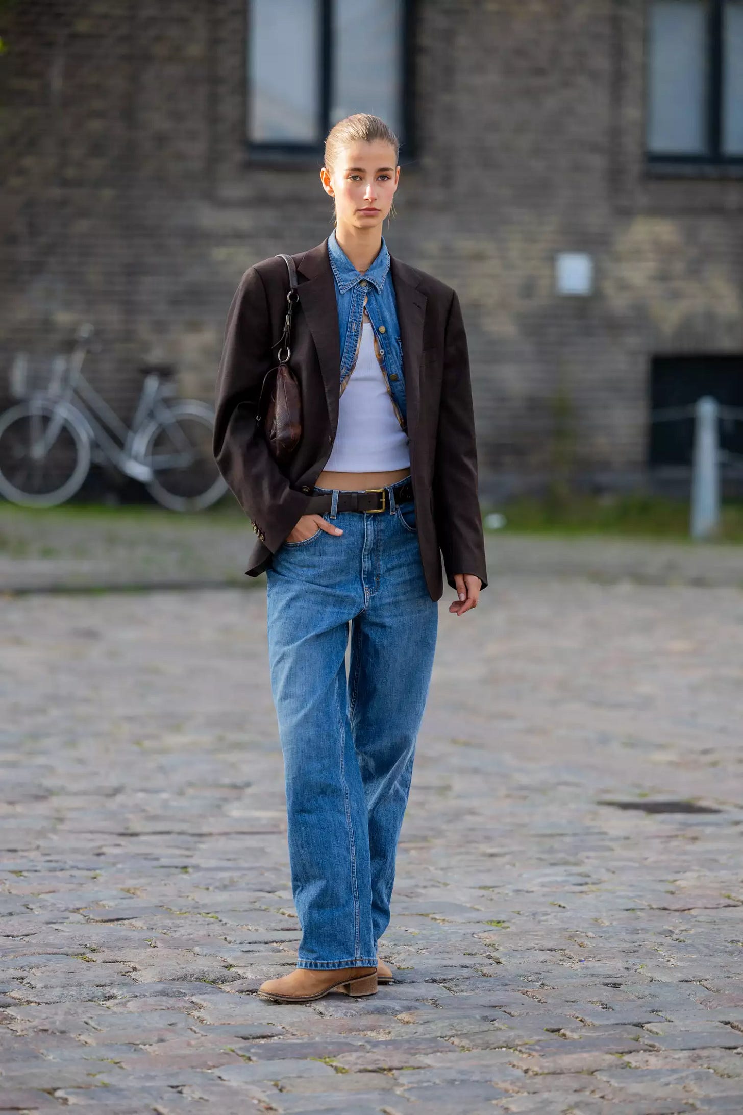 Person wearing brown blazer over denim shirt and pants