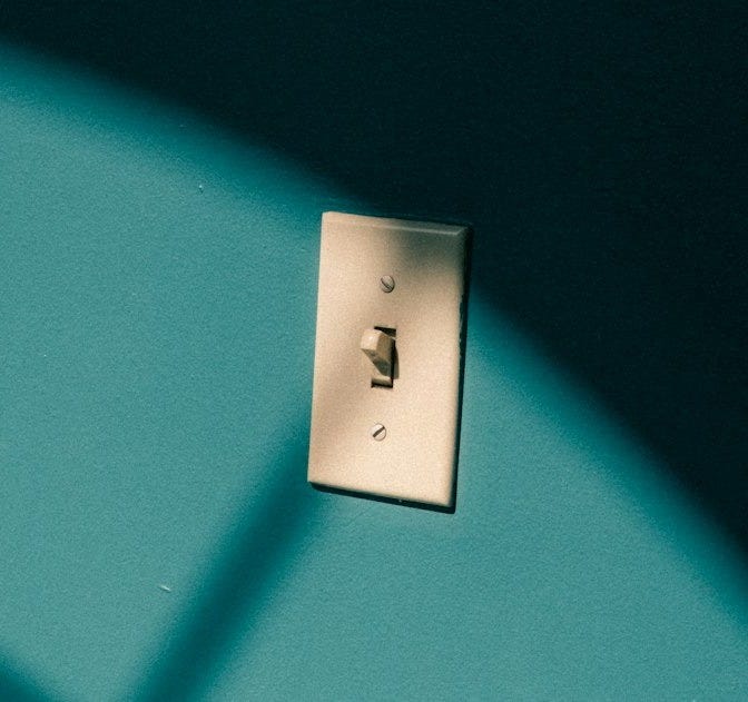 Light switch on a teal wall with shadows.