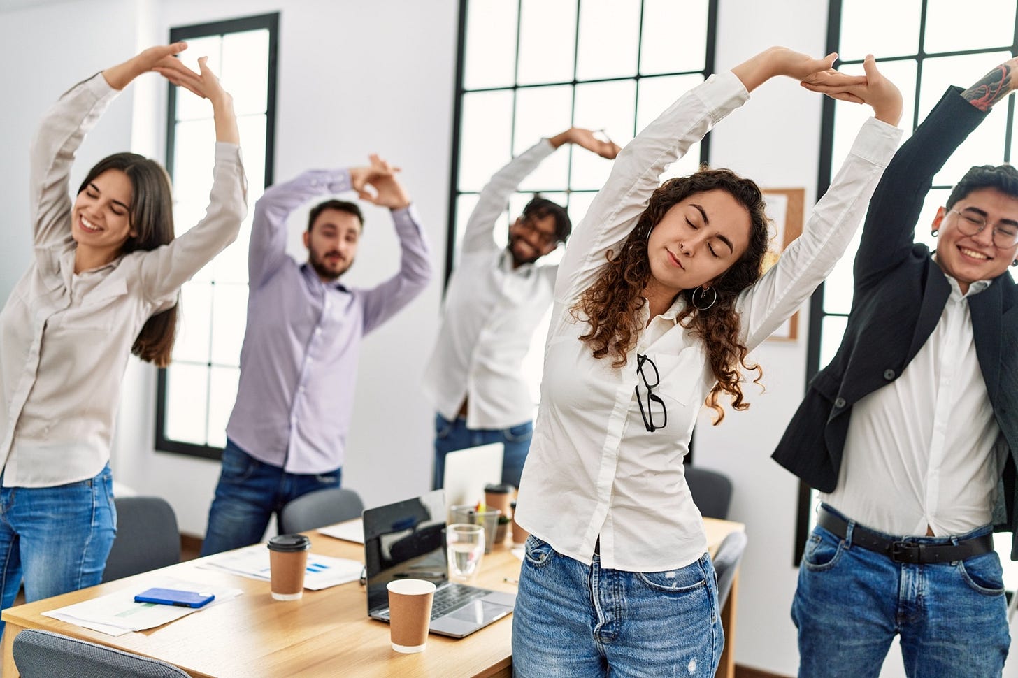 A group of people stretching in an office

Description automatically generated with medium confidence