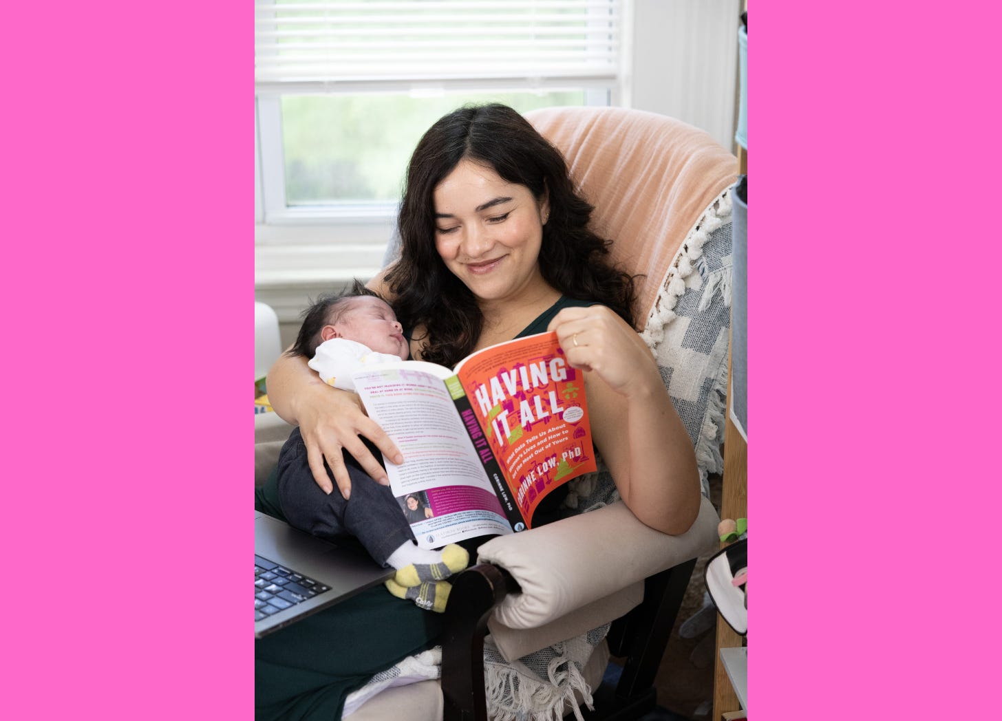 Woman smiling holding a baby and reading a book