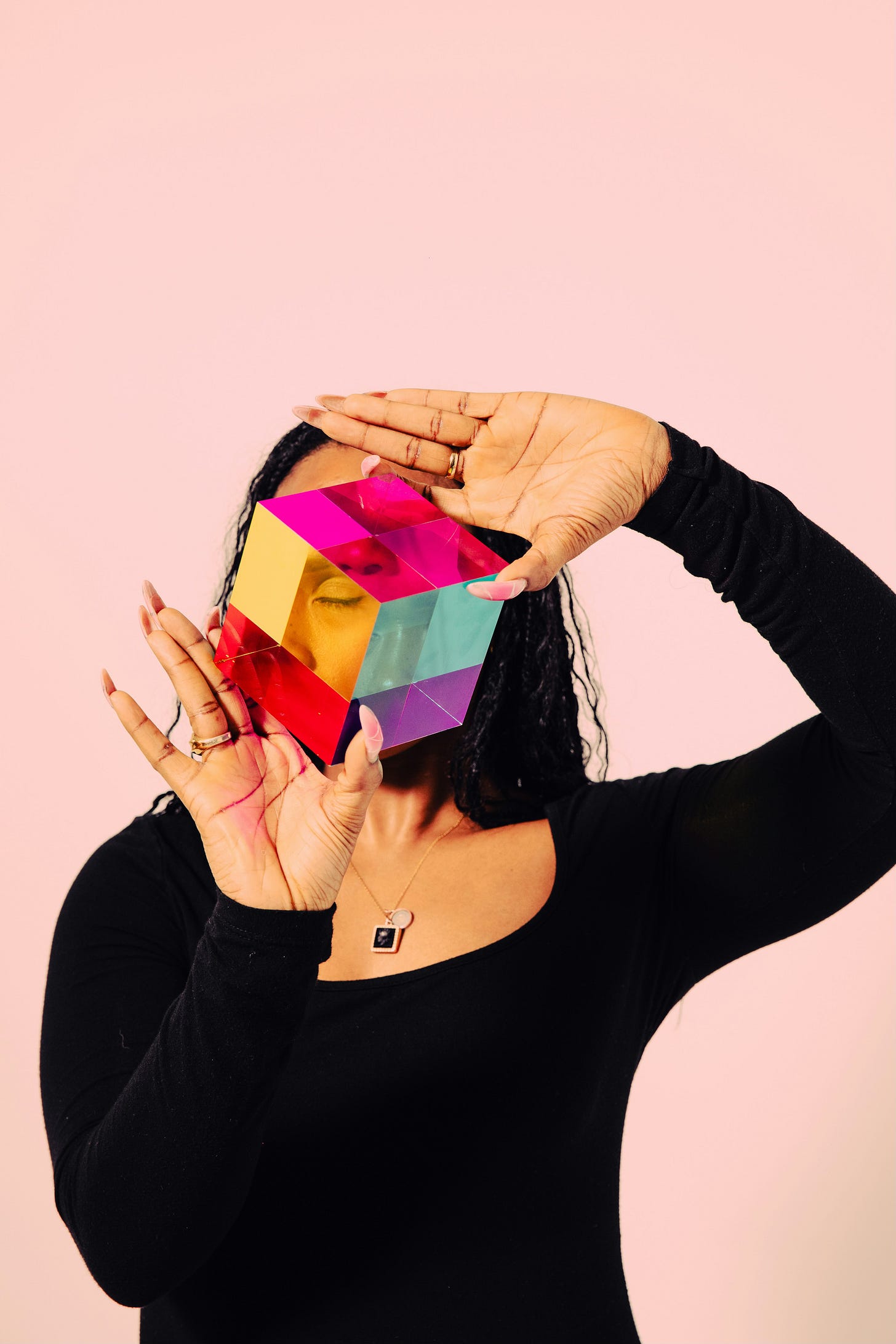 a lady holding a colourful cube in front of her face