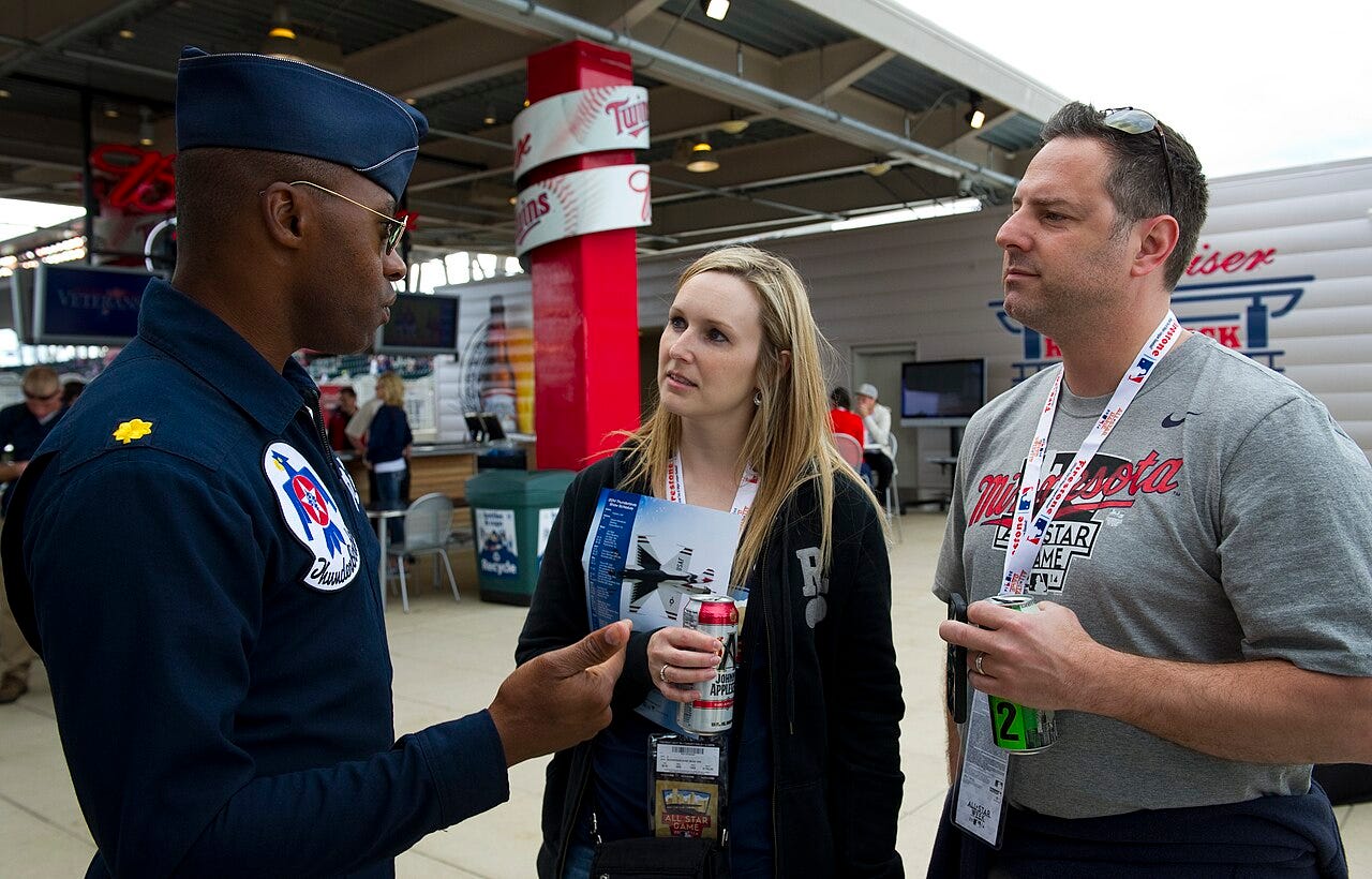 Photo: Master Sgt. Stan Parker / Wikimedia Commons (Public domain) Maj. Darrick Lee, Thunderbird 12, Public Affairs Officer, discusses the mission of the U.S. Air Force Thunderbirds with admiring fans prior to performing the flyover for the MLB All-Star Game, Minneapolis, Minnesota, July 15, 2014. (U.S. Air Force ph