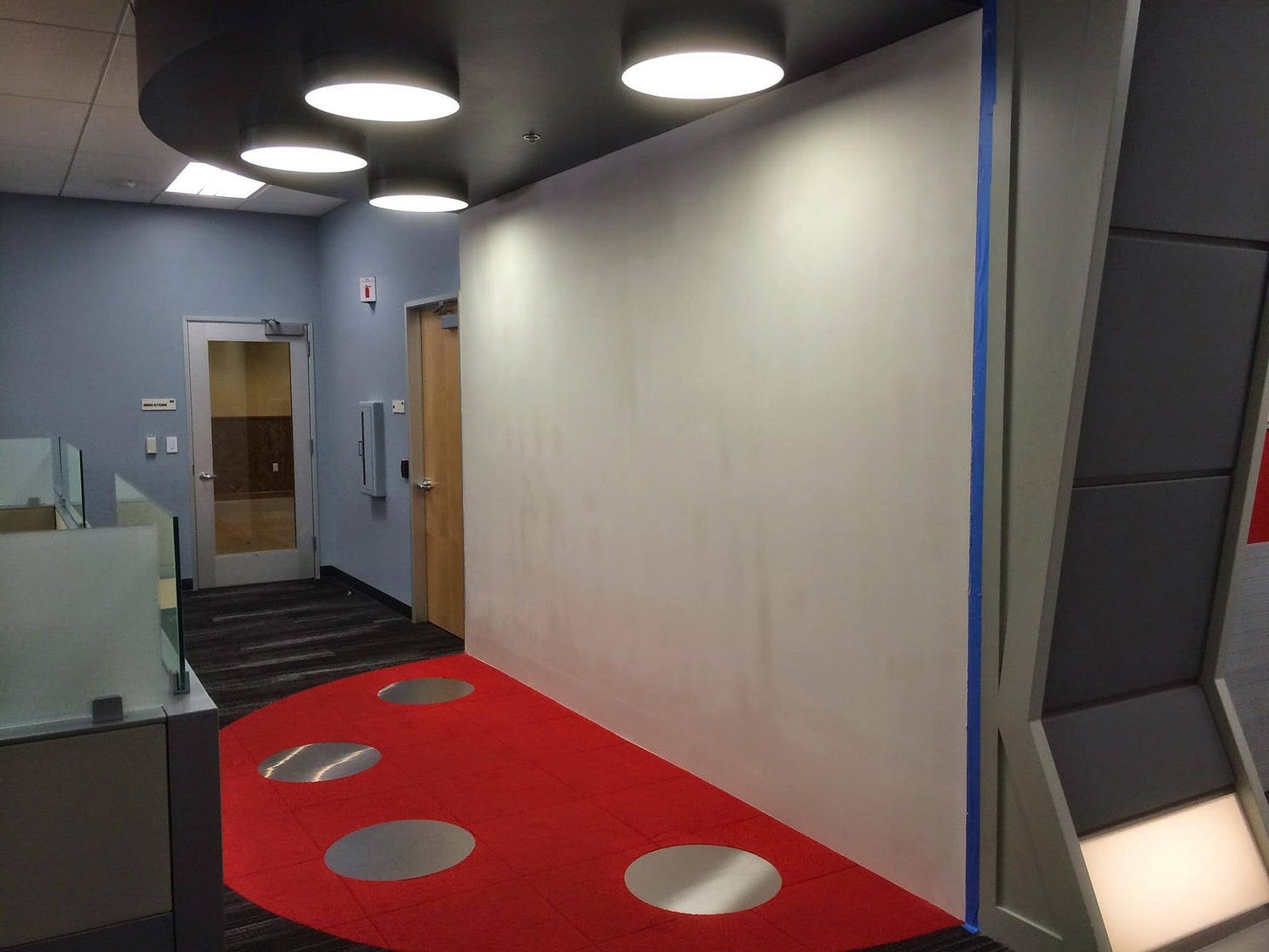 Image of typical corporate office with modular furniture. Along one wall is a replica of the transporter pad from Star Trek: The Original Series, or as I call it, Star Trek.