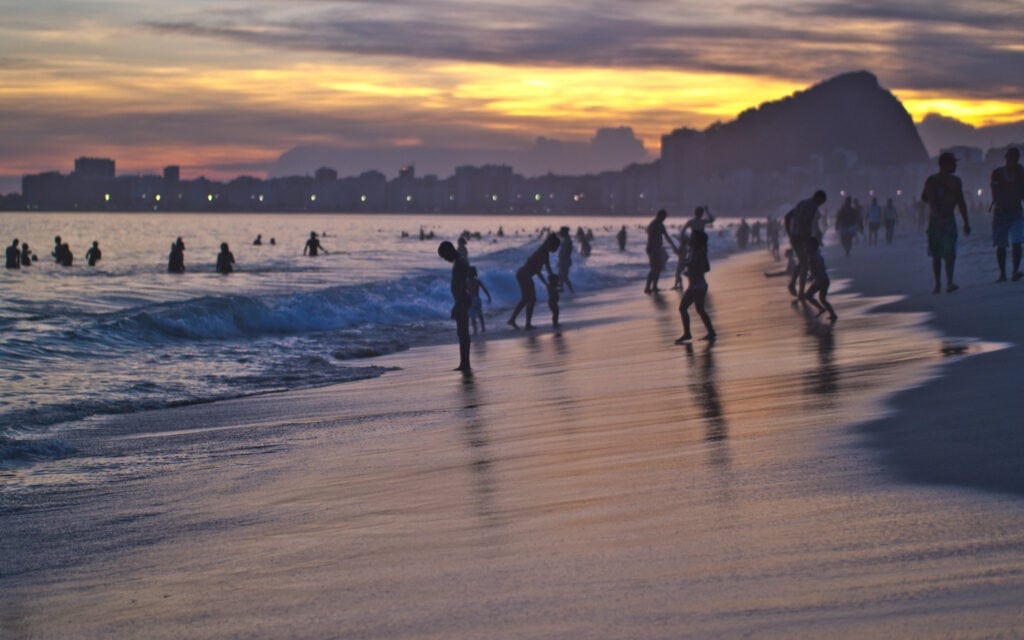 9 best beaches in Rio de Janeiro. beautiful sunset, people swimming in sandy beach