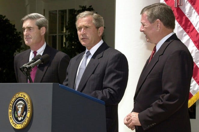 George W. Bush (center) with Robert Mueller (left) in a Rose Garden ceremony.
