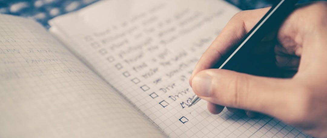 person writing bucket list on book person writing bucket list on book