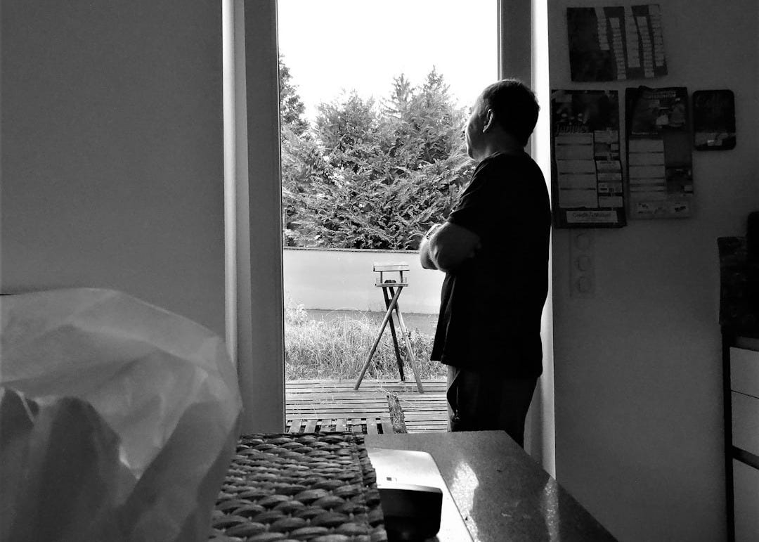 a black and white photo of a man standing in a doorway