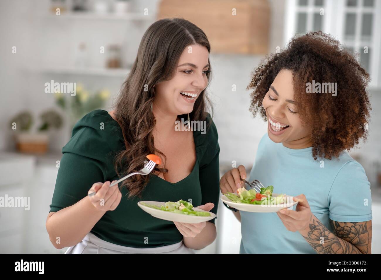 Laughing good looking women eating vegetable salad Stock Photo - Alamy