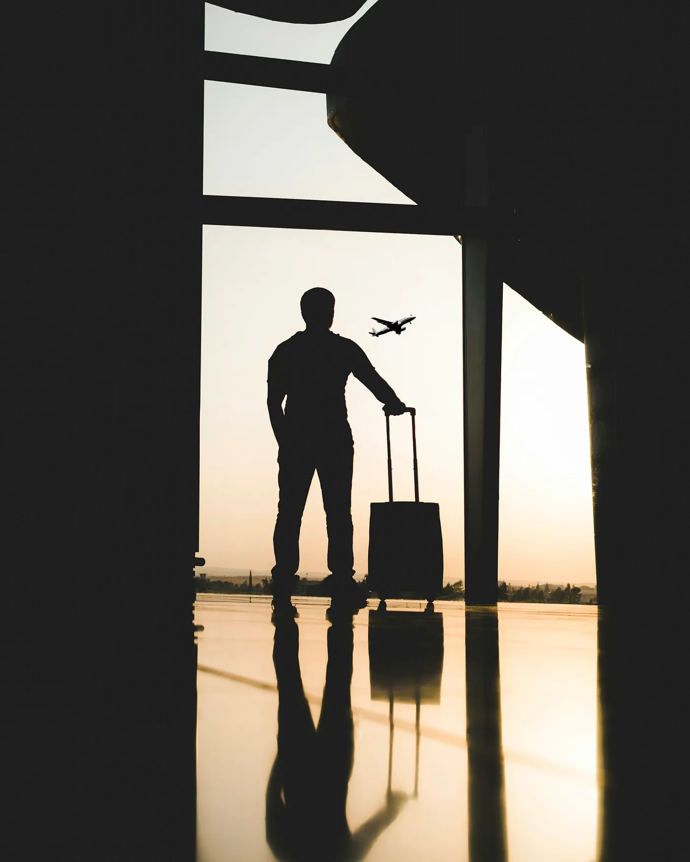 Silhouette of a man at an airport window looking out