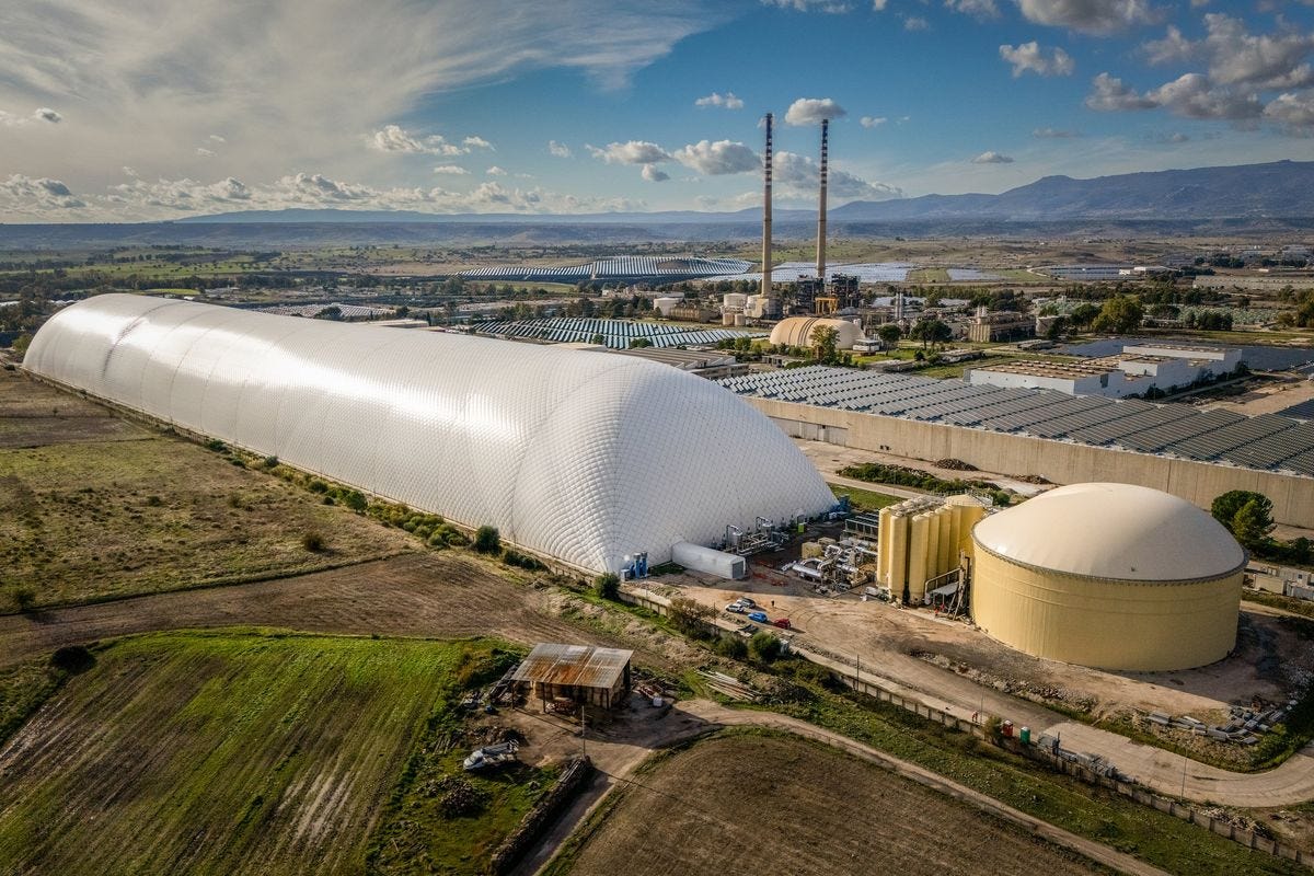 A white oblong dome bigger than a sports stadium, multiple tanks and a photovoltaic array on a rural landscape