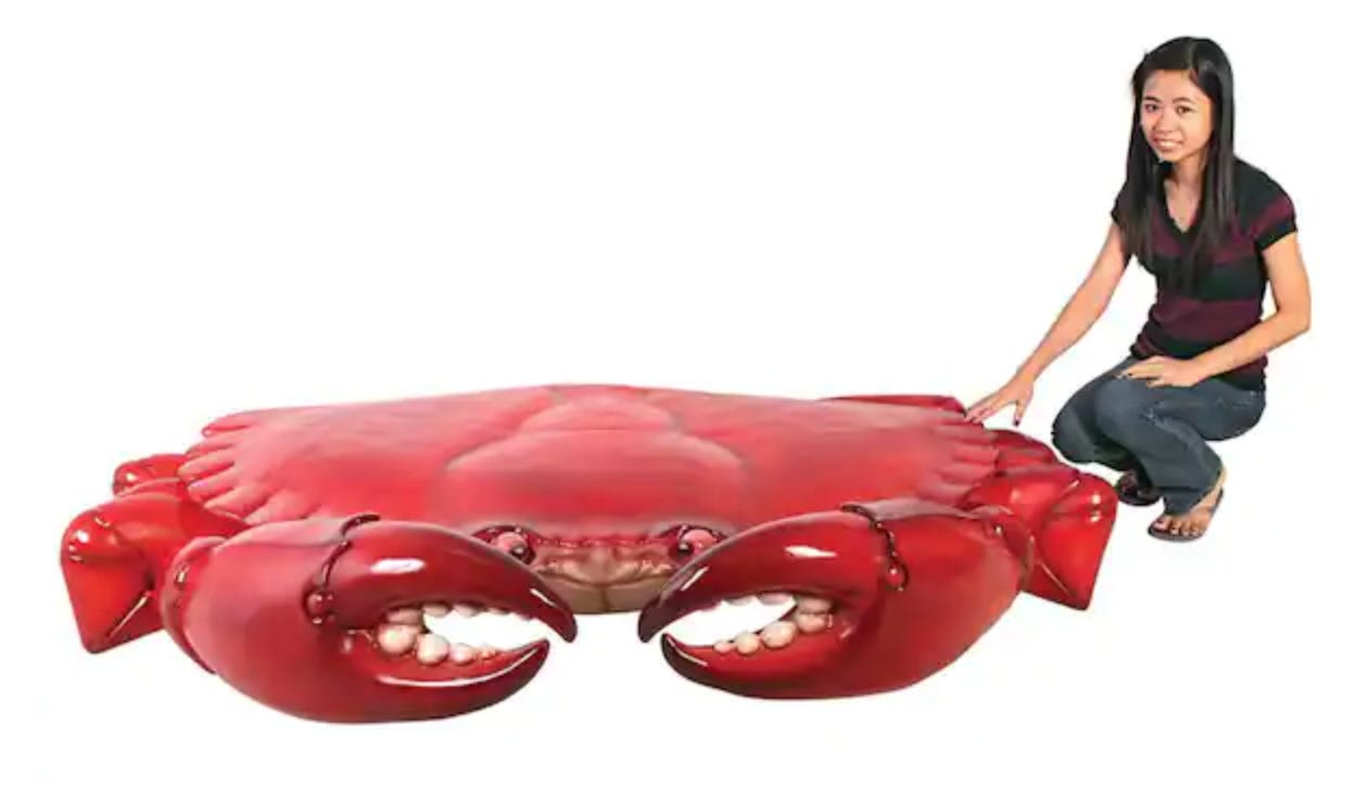 a resin statue of a giant crab. An Asian woman is squatting next to it, one hand gingerly touching it. She's smiling but looks uncomfortable