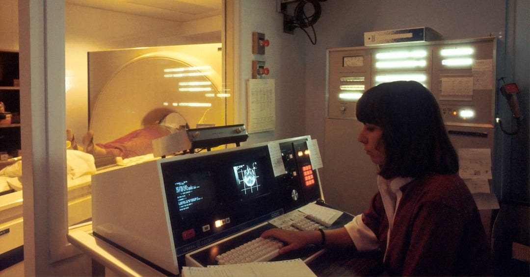 woman in red shirt sitting in front of computer woman in red shirt sitting in front of computer