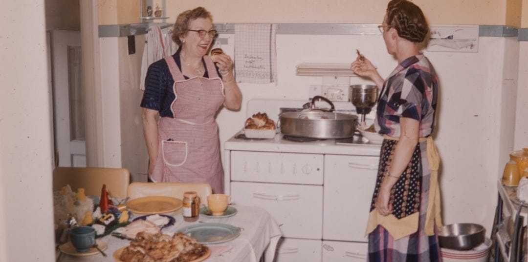 a couple of women standing in a kitchen