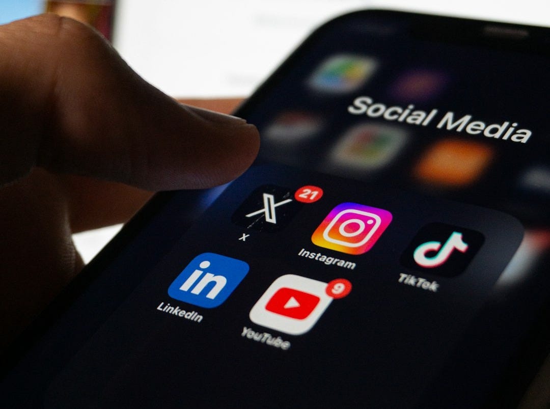 A person holding a smart phone with social media on the screen