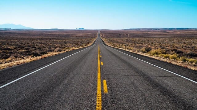 gray concrete road in middle of brown grass field photo