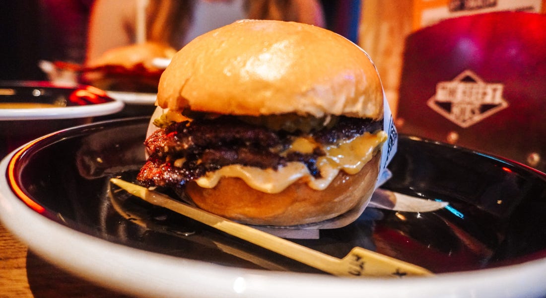 A brioche bun with a burger patty in it, on a black plate