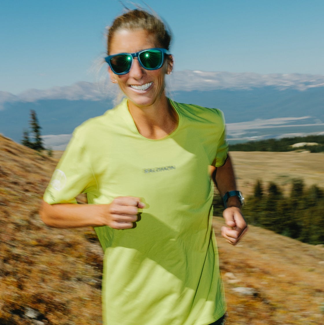 Person running on a grassy slope with a mountainous background Person running on a grassy slope with a mountainous background