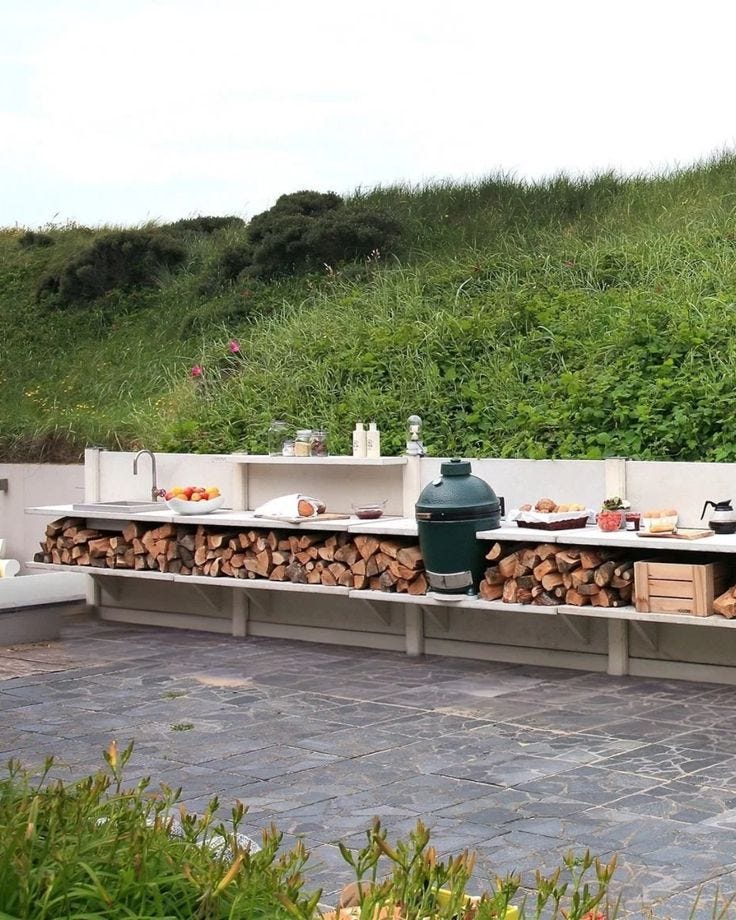 This may contain: an outdoor bbq with lots of wood stacked on it