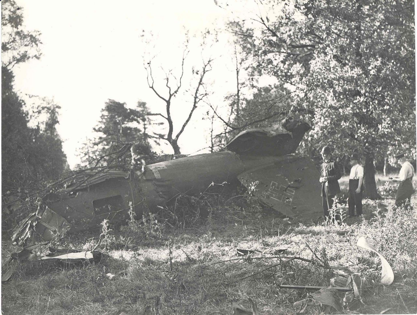 Three officers inspect the wreckage of a German bomber.
