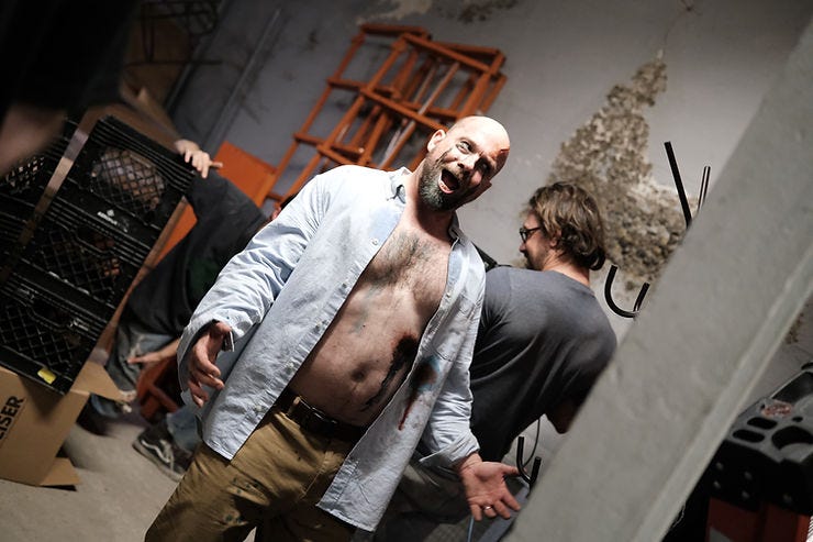 An actor stands in bloody makeup with his shirt open on a film set. An actor stands in bloody makeup with his shirt open on a film set.