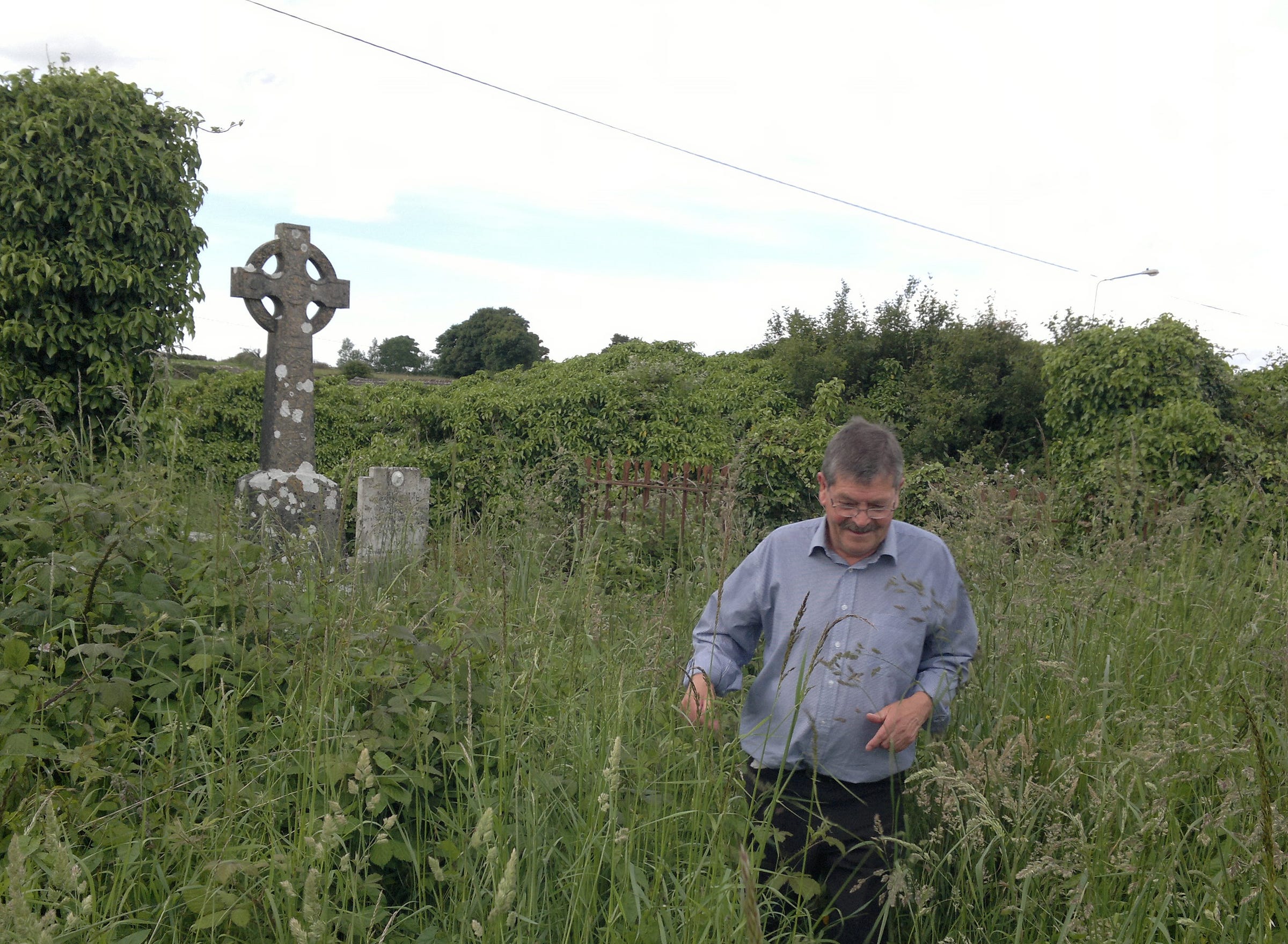 Man in a blue shirt walks through elbow-high grass.