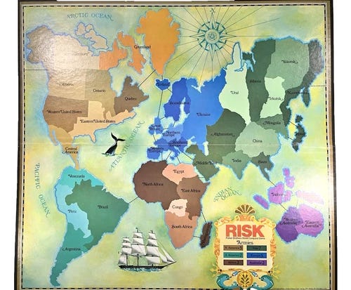 Vintage 1975 RISK board game map with green and orange continent divisions, black mountain ranges, and yellow text.